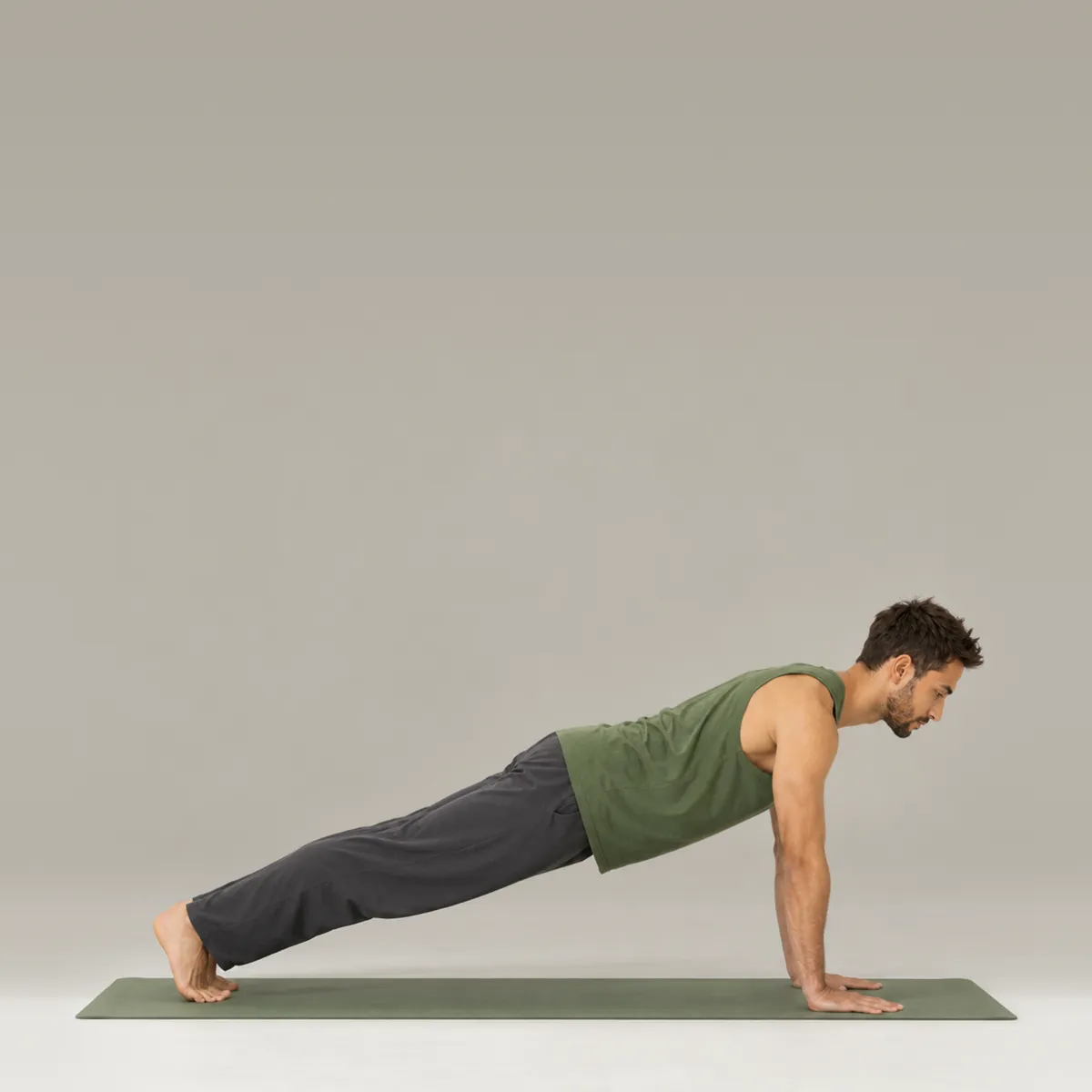 A man holding plank pose on a green yoga mat, body in one long line from head to heels